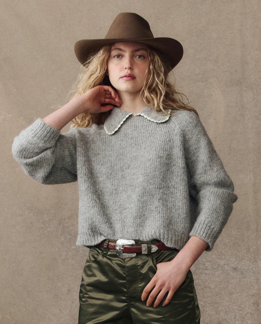 grey cardigan on a model with green pants and a western hat on a cream background, front