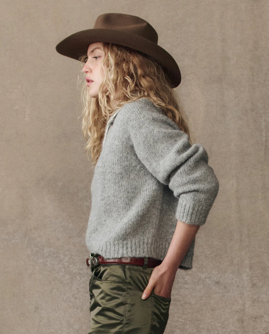 grey cardigan on a model with green pants and a western hat on a cream background, side