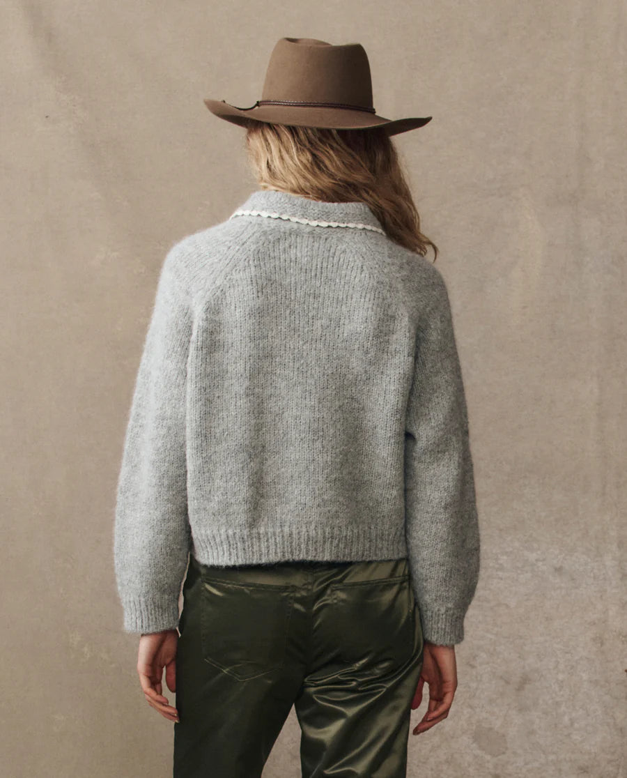 grey cardigan on a model with green pants and a western hat on a cream background, back