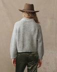 grey cardigan on a model with green pants and a western hat on a cream background, back