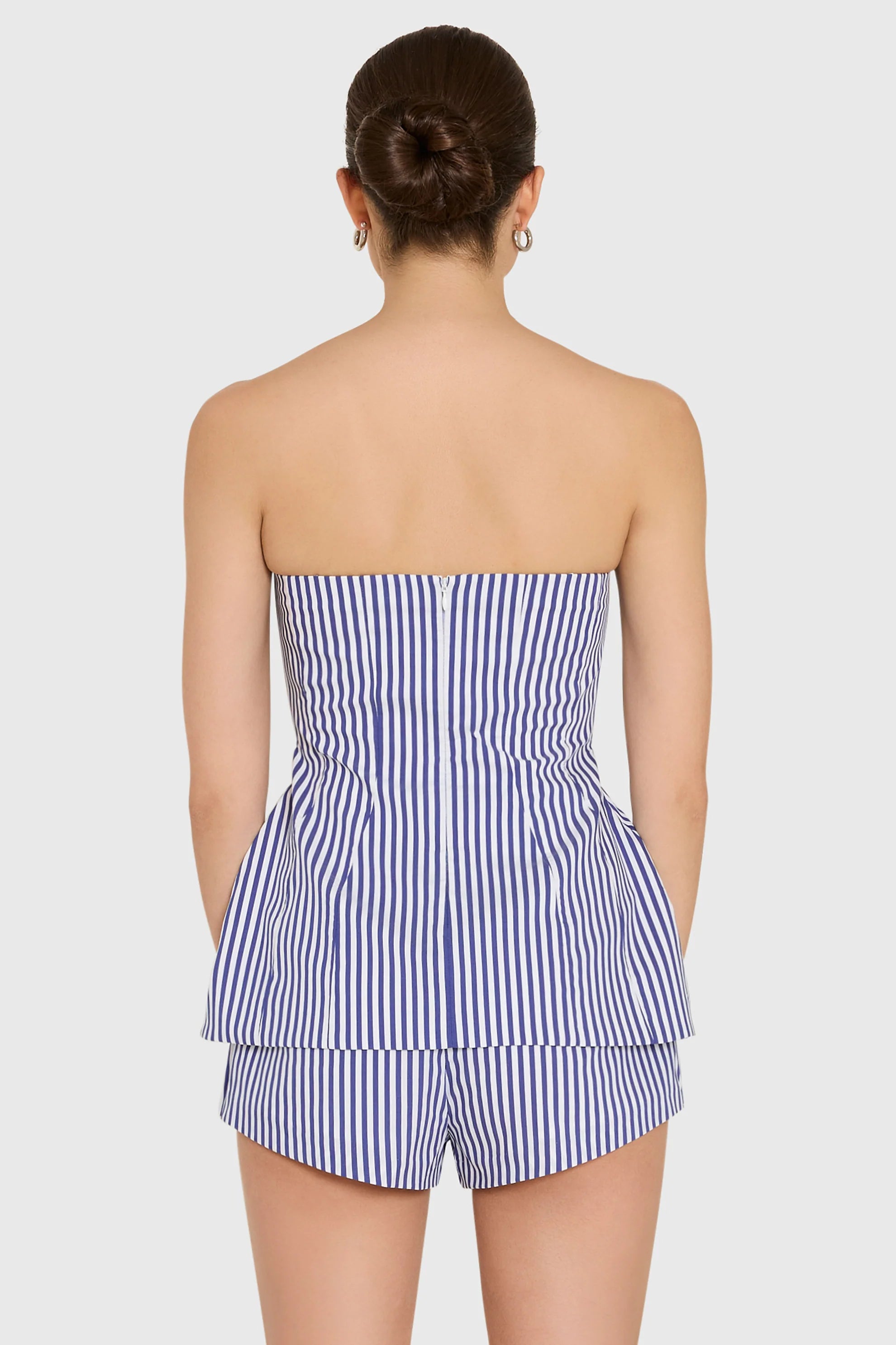 model wearing a strapless top and short set in blue and ivory stripes, back view
