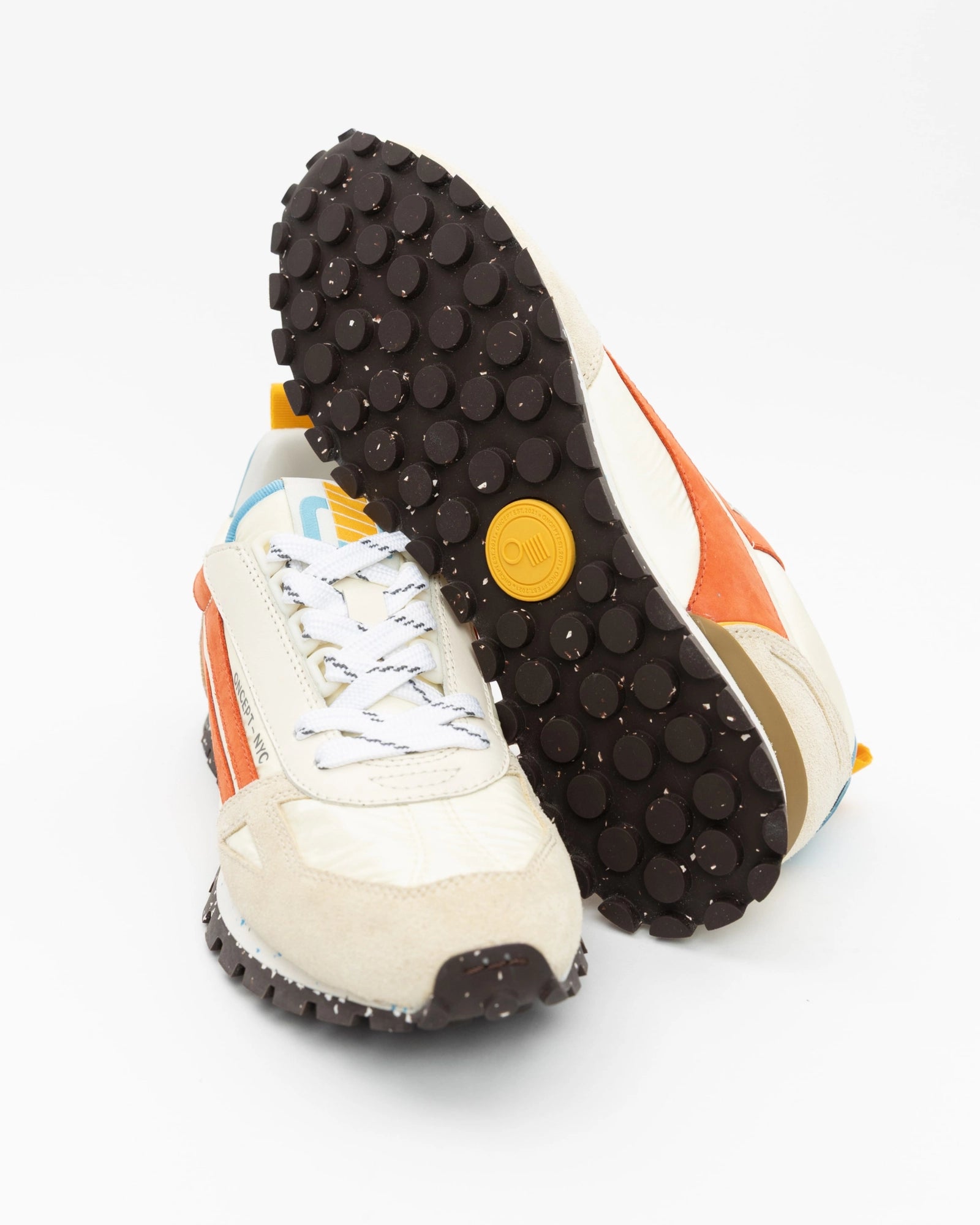 Close-up of a white sneaker with orange accents and a black sole on a white background