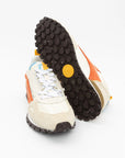 Close-up of a white sneaker with orange accents and a black sole on a white background