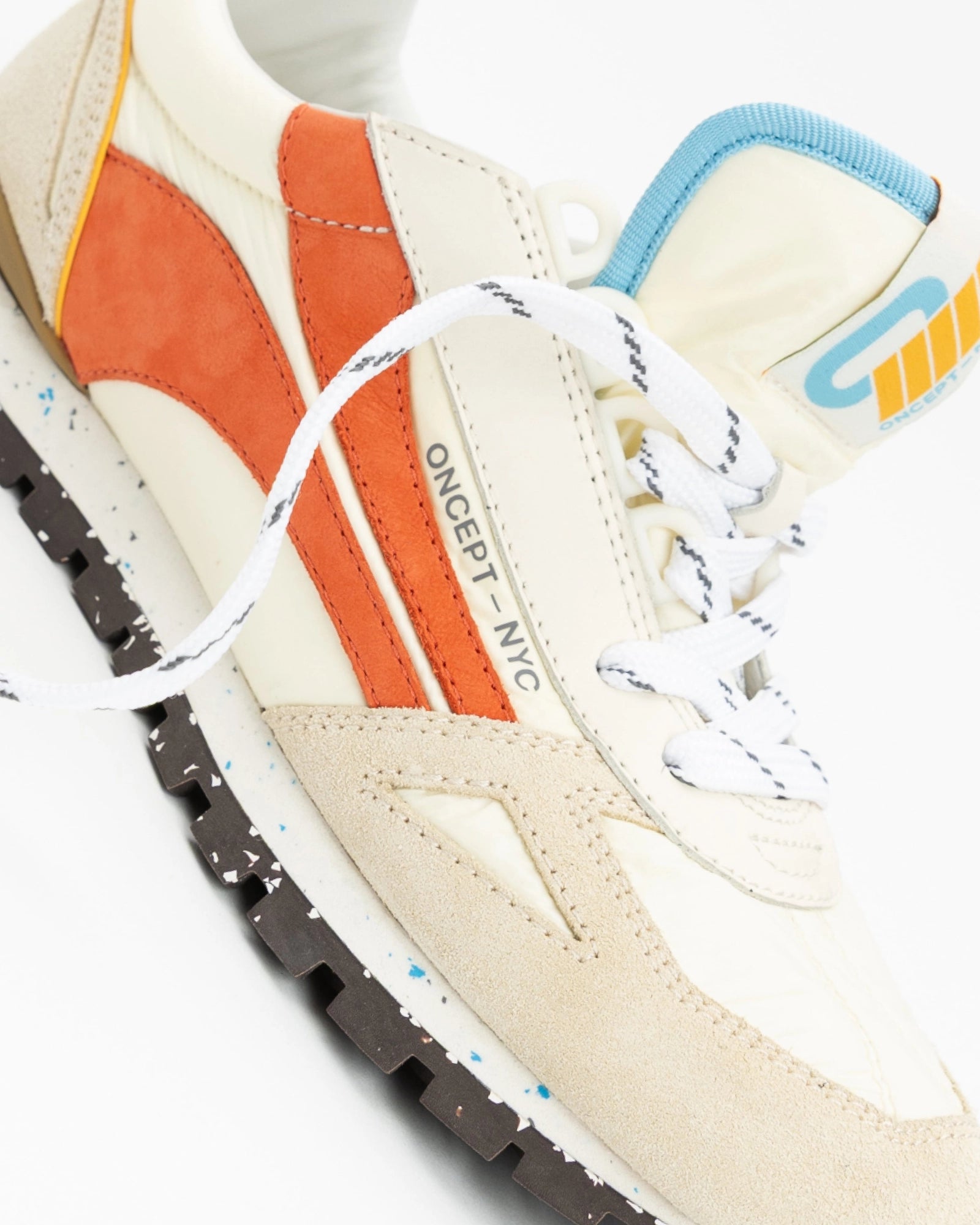 Close-up of a sneaker with orange, blue, and white accents on a white background