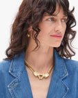 Woman wearing a gold necklace and earrings with a blue denim jacket on a white background