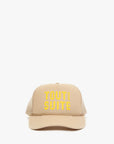 A beige trucker-style cap with yellow embroidered text reading 'TOUT DE SUITE' on the front, shown against a plain white background.