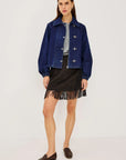 model wearing a fringe plaid skirt with a grey top and jacket, loafers, on a light grey background 