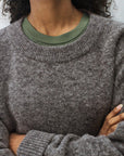 Person wearing a gray sweater with a green t-shirt