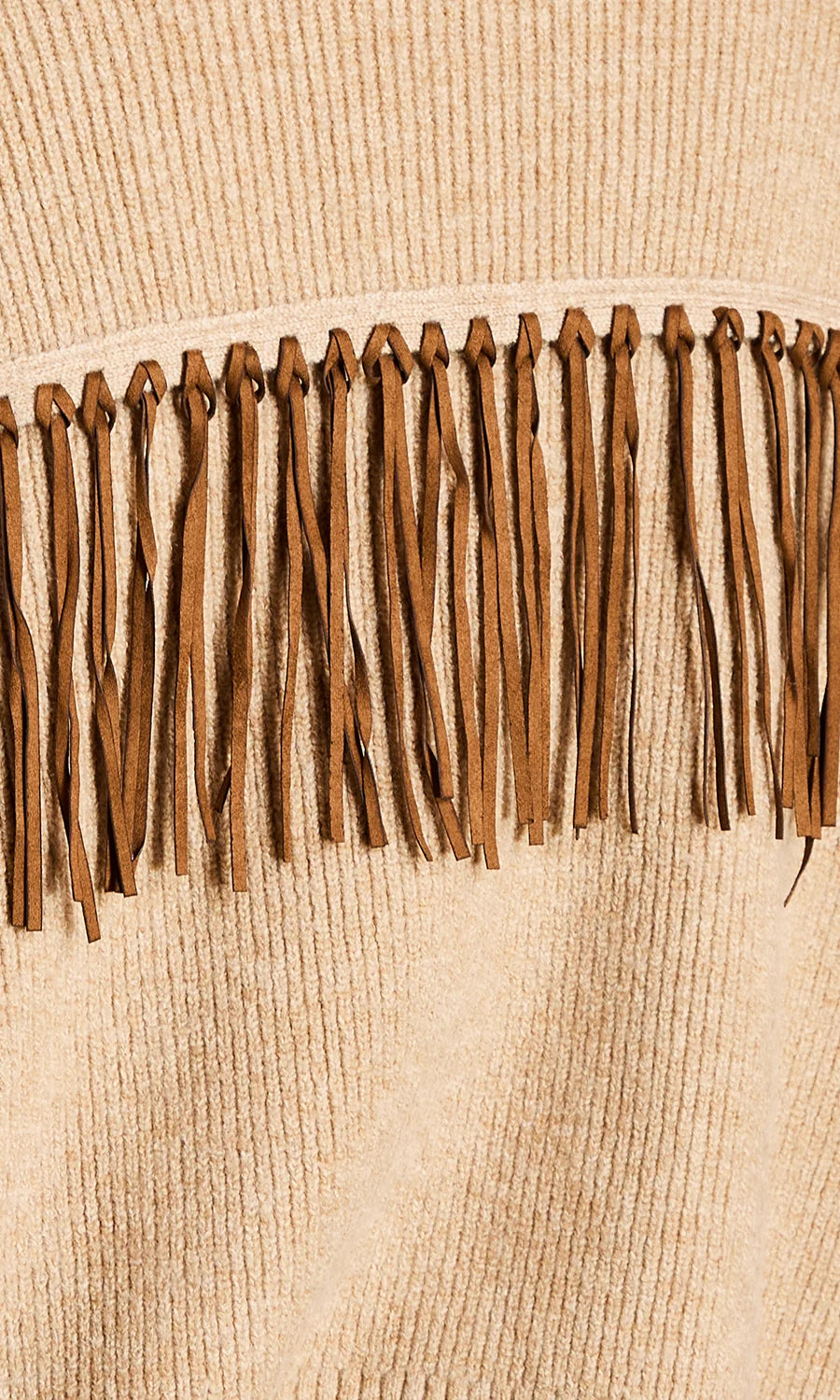 Close-up of a beige ribbed knit garment with a horizontal band of medium brown fringe trim across the chest.