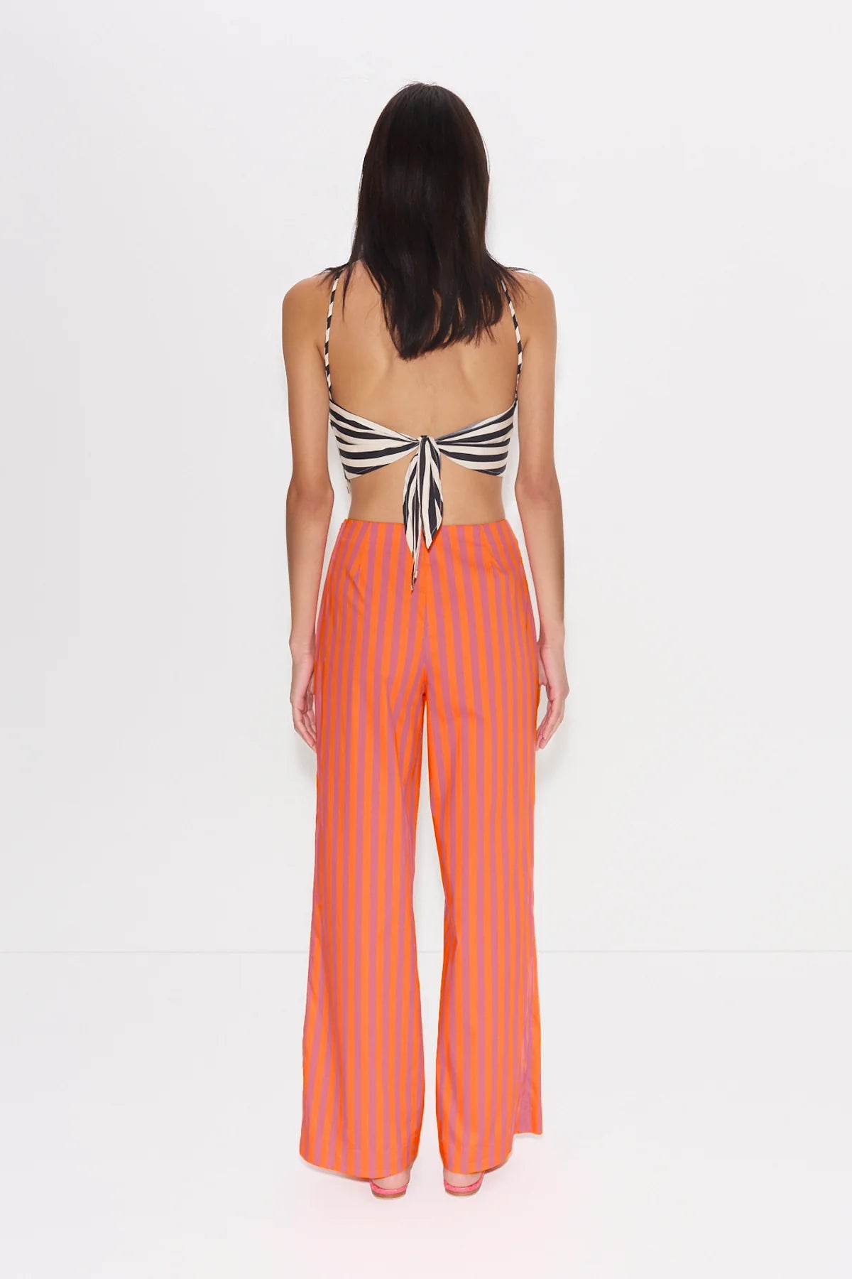 Woman wearing a striped top and orange pants on a white background