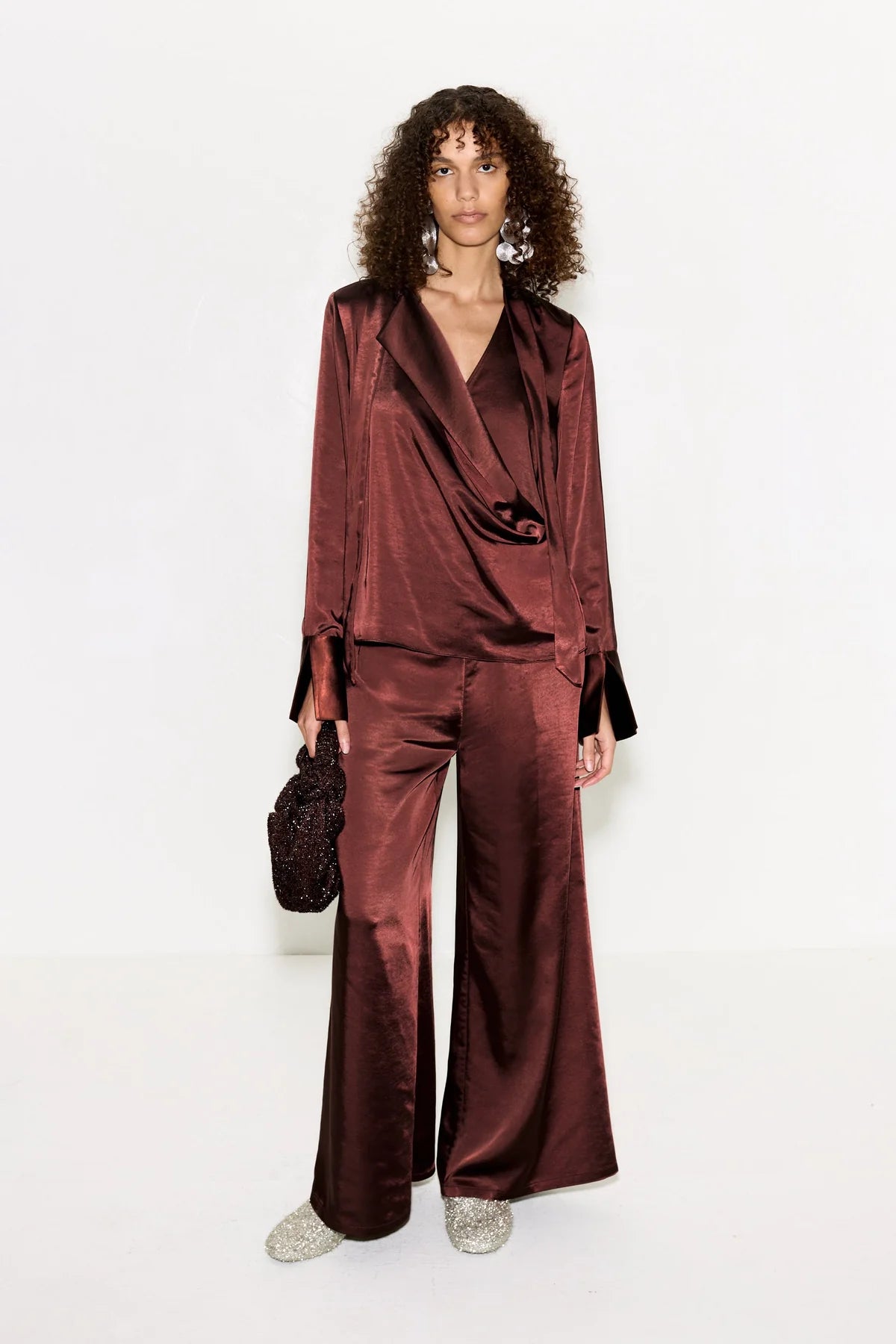 Woman wearing a burgundy satin suit with a white background