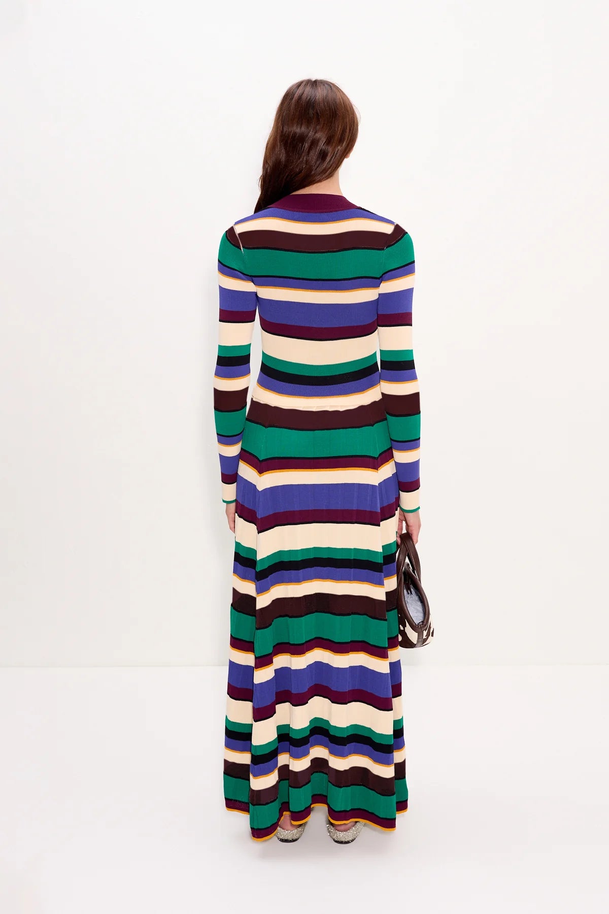 Woman wearing a long, multicolored striped dress on a white background