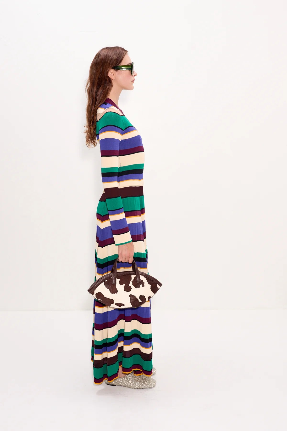 Woman wearing a long, multicolored striped dress on a white background