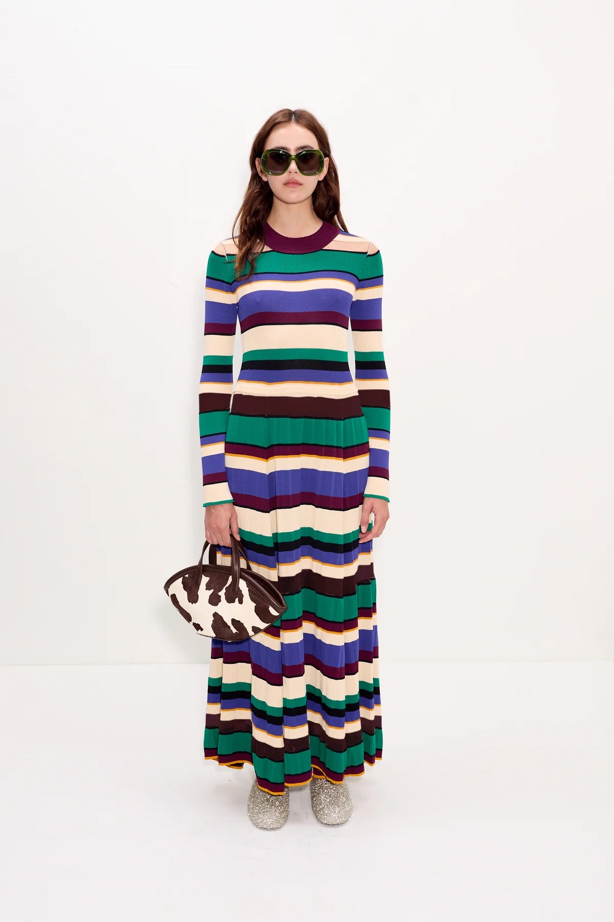 Woman wearing a long, multicolored striped dress on a white background