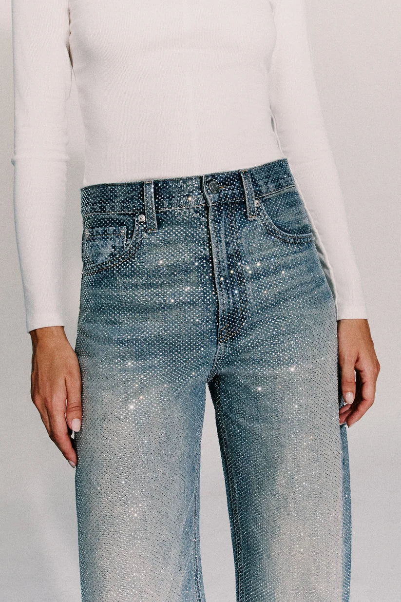 close up of a blue jean covered in rhinestones with a white long sleeve top 