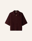 A dark burgundy short-sleeve knit polo shirt with a single gold button, displayed flat against a light cream background.