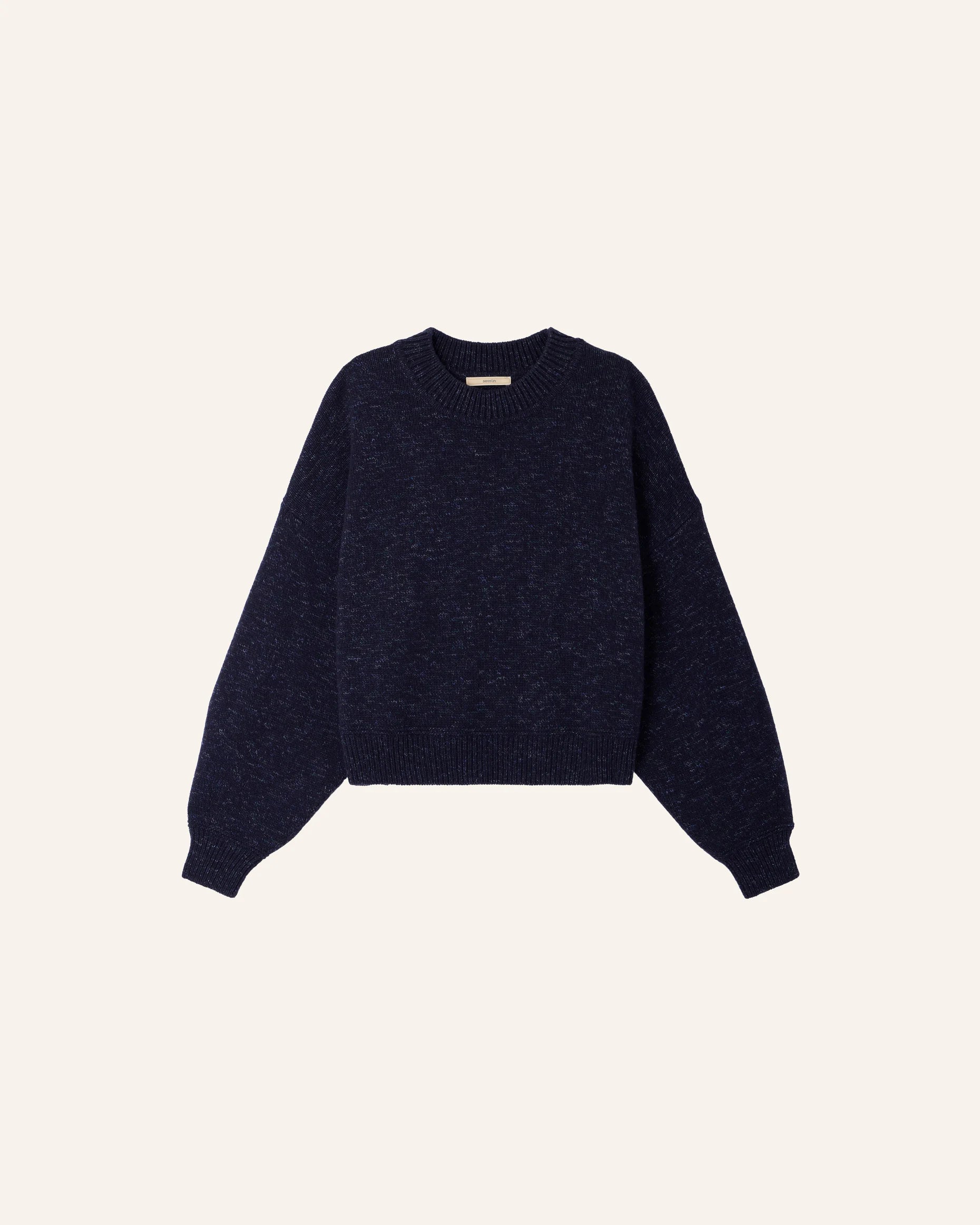 A dark navy blue knit sweater with balloon sleeves, shown flat against a light cream background.