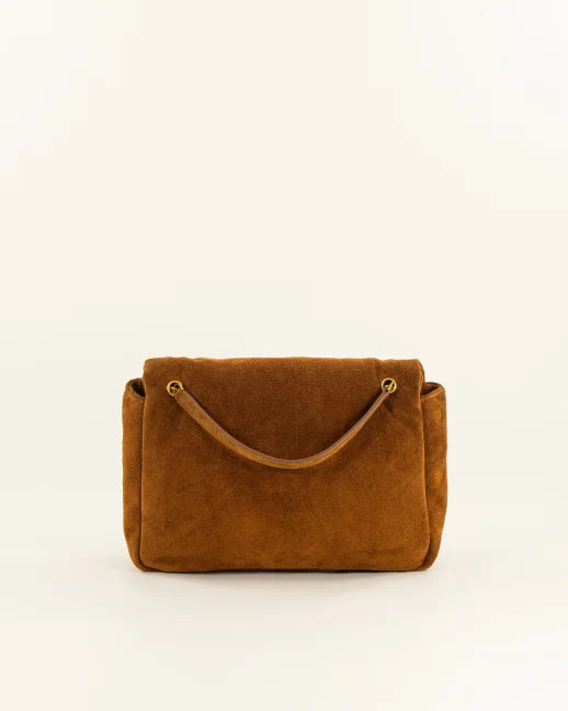 A brown suede handbag with a top handle and gold-tone hardware, photographed against a plain off-white background.