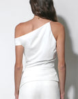 A woman shown from the back wearing a white one-shoulder top and matching white pants against a plain light gray studio background.