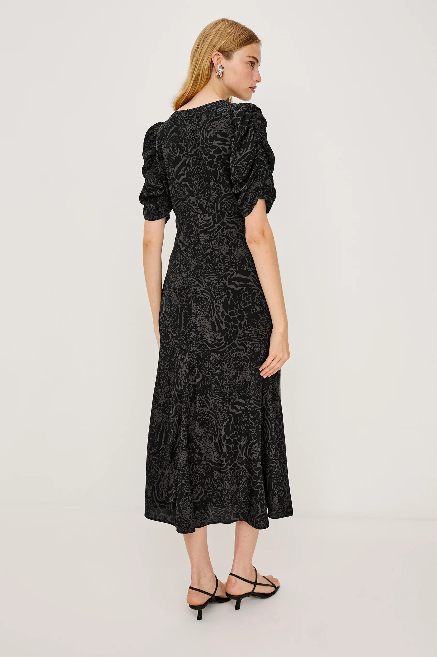 Woman wearing a black patterned dress on a light gray background