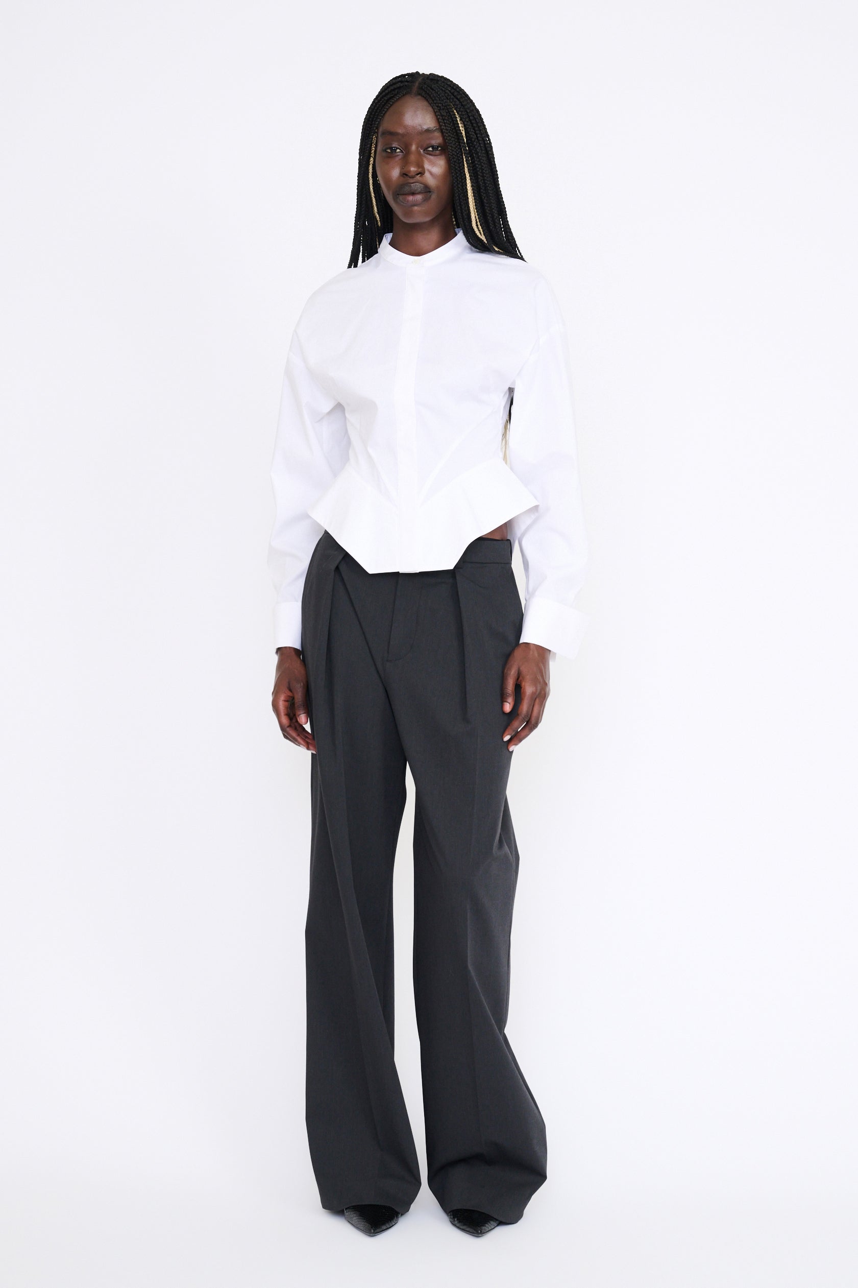 Person wearing a white blouse and black pants on a white background