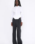Person wearing a white blouse and black pants on a white background