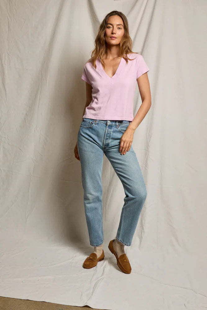 Woman wearing a pink top and blue jeans against a plain background
