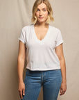 Woman wearing a white t-shirt and blue jeans against a beige background, size L