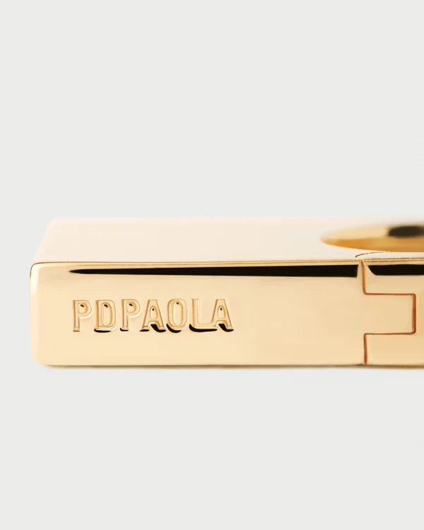 Gold bracelet with &#39;PDPAOLA&#39; engraving on a light gray background