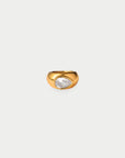 A gold ring featuring a teardrop-shaped clear gemstone, set against a solid light gray background.