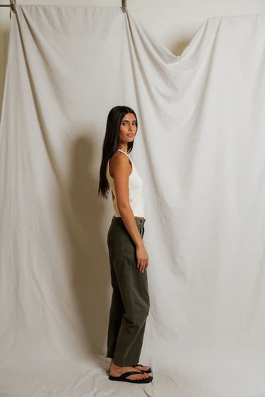 Woman standing against a plain white curtain