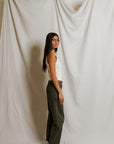 Woman standing against a plain white curtain