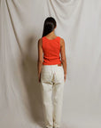 Person wearing a red top and white pants standing against a plain background