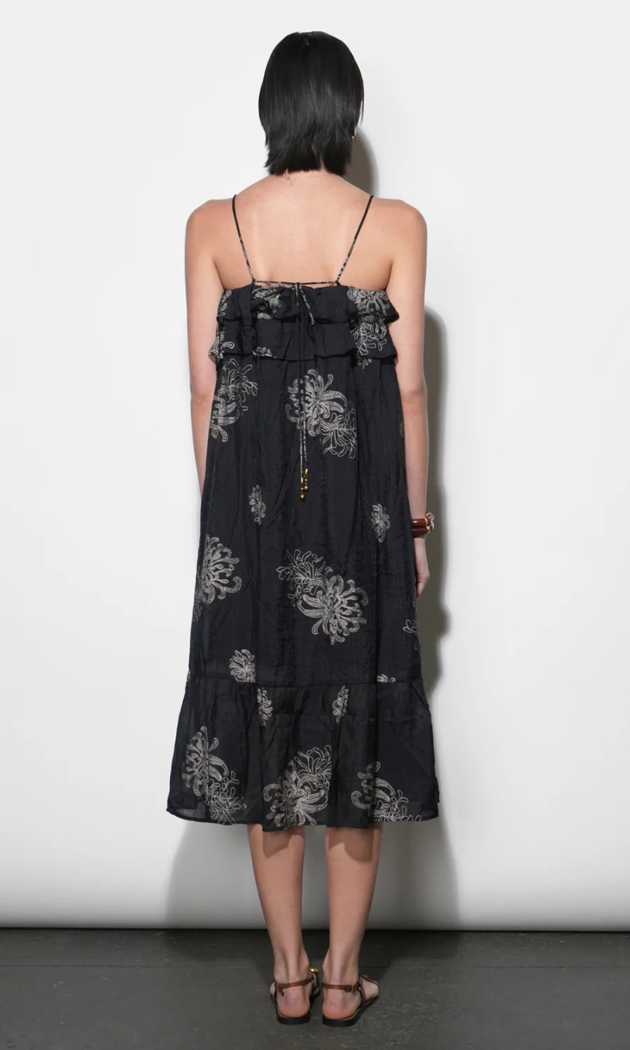 model wearing the Paige Layered Ruffle Midi Dress with strappy sandals on a white background, back