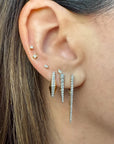 A close-up of a person's ear wearing a pair of long, dangling diamond earrings with multiple thin vertical strands.