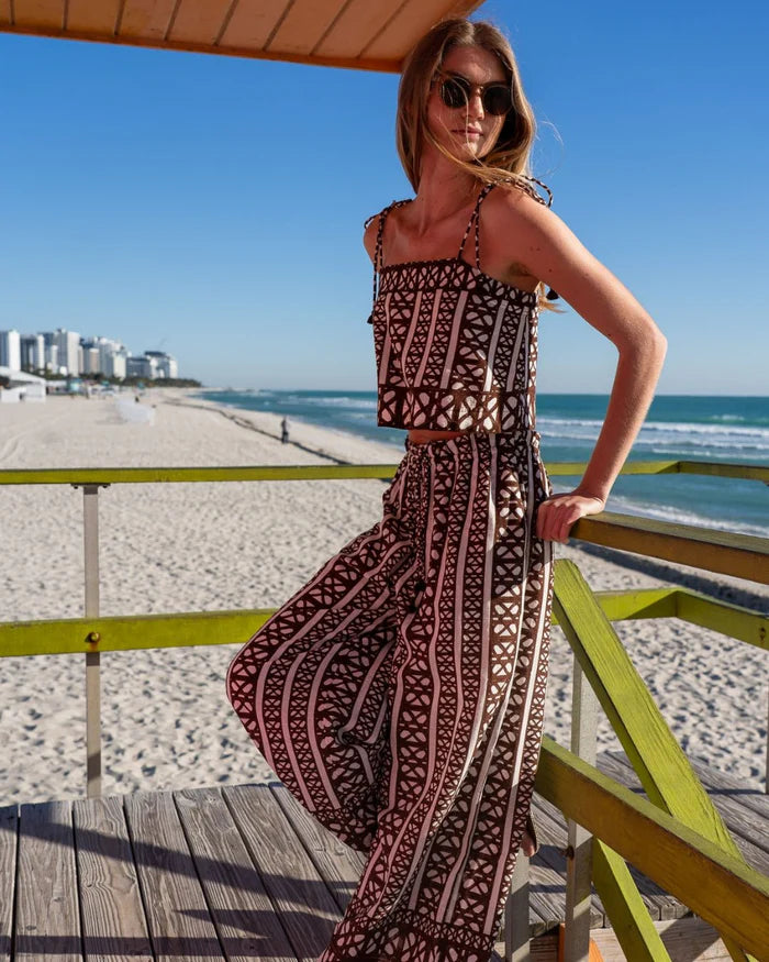 Woman in a patterned set standing on a beach with ocean and skyline in the background