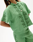 Green embroidered shirt and pants on a white background