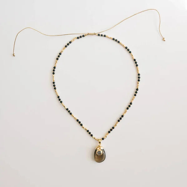 Necklace with black beads and a pendant on a light gray background