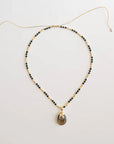 Necklace with black beads and a pendant on a light gray background