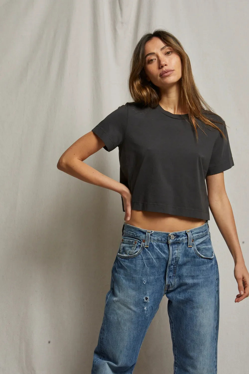 model wearing cher short sleeve vintage black tee with jeans on a cream background