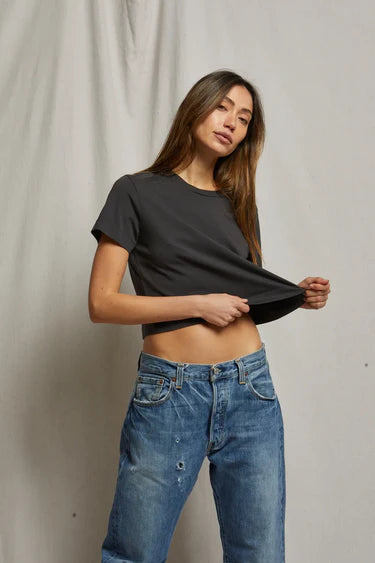 model wearing cher short sleeve vintage black tee with jeans on a cream background