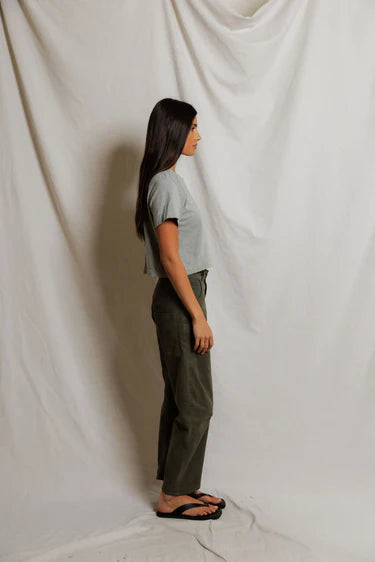 model wearing a heather grey t shirt and green pants on a white background, side view