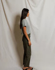 model wearing a heather grey t shirt and green pants on a white background, side view