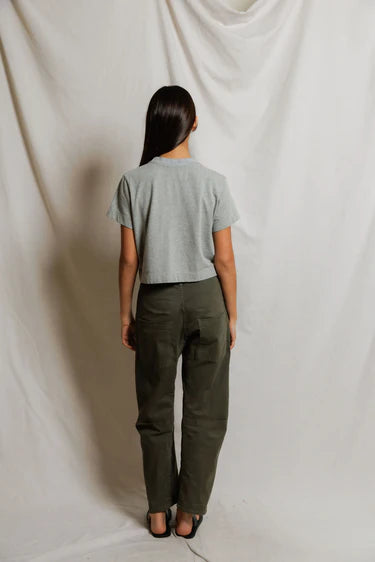 model wearing a heather grey t shirt and green pants on a white background, back view