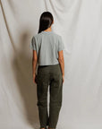 model wearing a heather grey t shirt and green pants on a white background, back view
