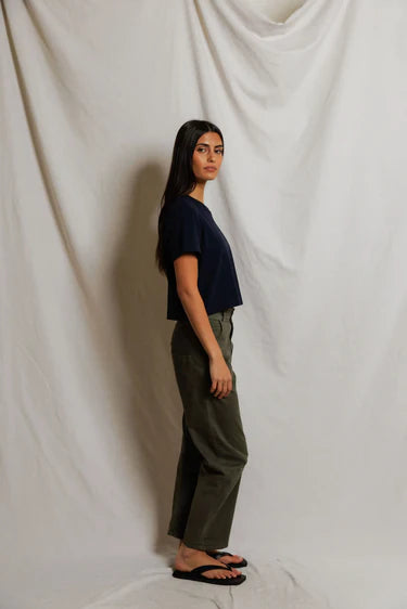 Cher Navy short sleeve tee on a model with green pants and a cream background