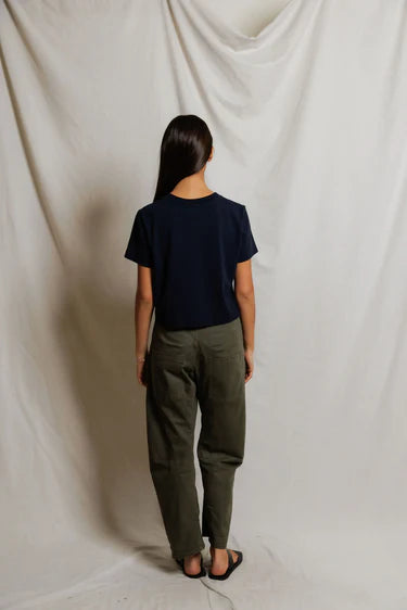 Cher Navy short sleeve tee on a model with green pants and a cream background, back