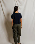 Cher Navy short sleeve tee on a model with green pants and a cream background, back