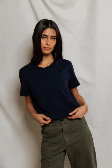 Cher Navy short sleeve tee on a model with green pants and a cream background