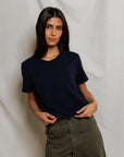 Cher Navy short sleeve tee on a model with green pants and a cream background